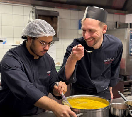 Apprenti en cuisine et formateur chef cuisinier souriant