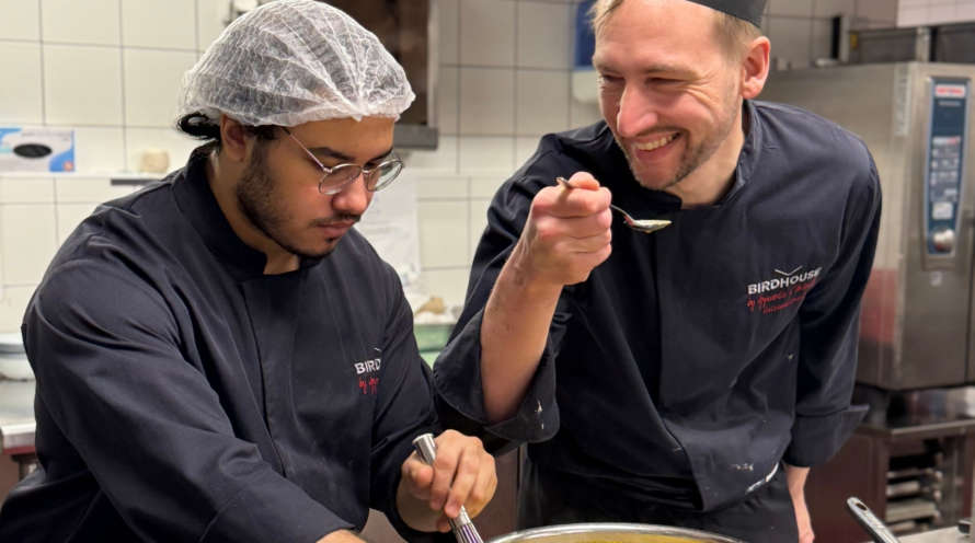 Apprenti en cuisine et formateur chef cuisinier souriant