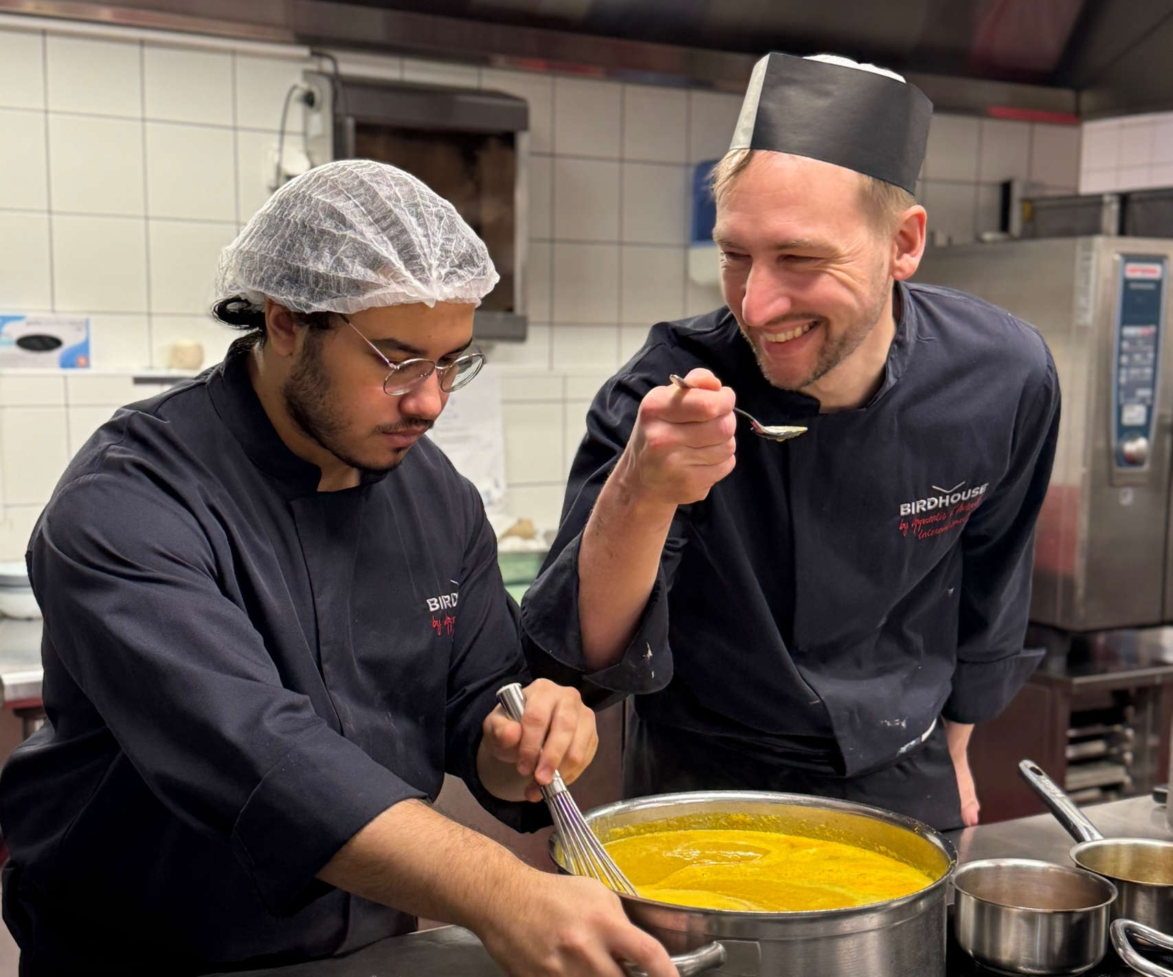 Apprenti en cuisine et formateur chef cuisinier souriant